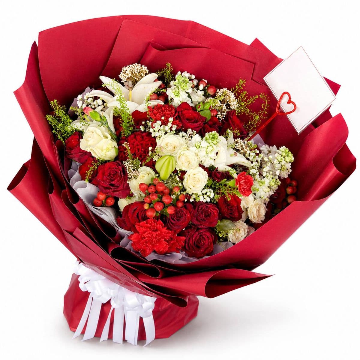 A luxurious romantic bouquet of red roses, white lilies, and red carnations wrapped in dark red paper with a white ribbon.